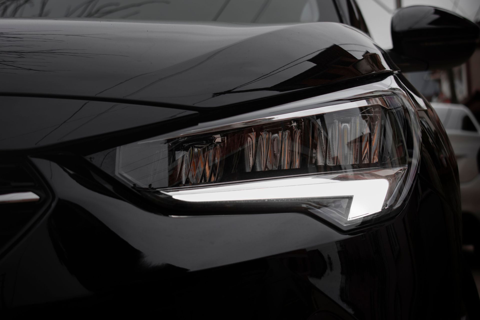Close-up of a sleek black modern car's headlight showcasing luxury design.